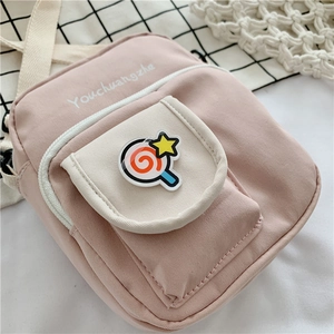 Detail view of pink canvas crossbody bag with lollipop badge and outer pocket