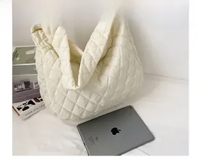Detail view of large quilted puffer tote bag shown with daily essentials for scale