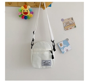 Close-up of a mini white canvas crossbody bag with Augur logo and adjustable strap