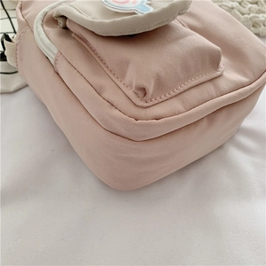 Detail view showing the bottom and side structure of the pink canvas crossbody bag