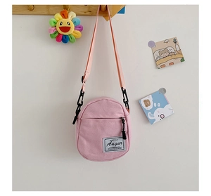 Pink canvas crossbody bag featuring adjustable straps and a woven Augur brand tag