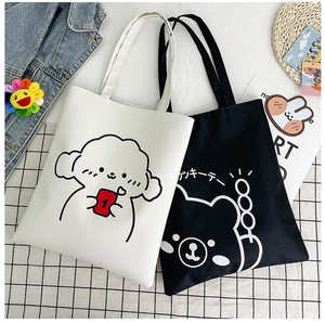Detailed flat lay of black and white canvas tote bags with cute cartoon dog and bear prints