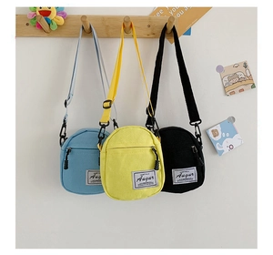 Detailed view of mini canvas crossbody bags in blue, yellow, and black colors