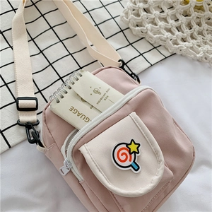 Detail of pink canvas crossbody bag with lollipop patch and white front pocket