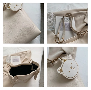 Detailed view of embossed cartoon patterns and soft leather texture on a beige tote bag