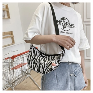Detail of zebra pattern half-moon crossbody bag with cute cow plush charm and wide strap