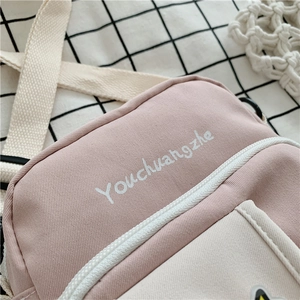 Detail of canvas shoulder bag in pink and beige with adjustable woven strap and zipper
