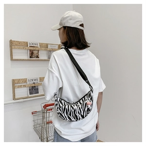 Detail of zebra print crescent crossbody bag with adjustable strap and cow charm accessory