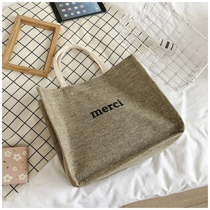 Close-up of linen tote bag with merci print and white cotton rope handles
