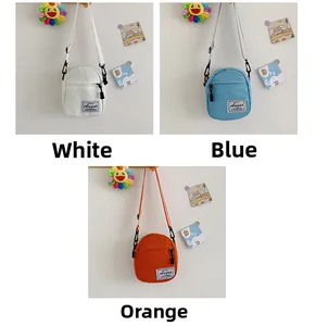 Detailed view of mini canvas crossbody bags in white, blue, and orange with brand label