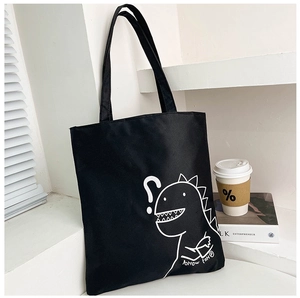Close-up of black canvas tote bag featuring a minimalist white cartoon dinosaur print