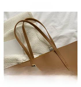 Detail shot of brown tote bag featuring synthetic leather and golden metal buckle