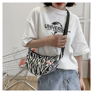 Detail of zebra print crescent bag featuring a cute cow pendant and wide strap