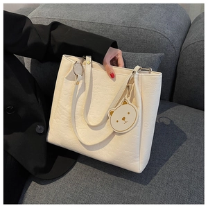 Detail of cream white tote bag with embossed cartoon patterns and cute bear charm