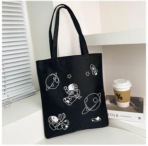 Detail of black canvas tote bag featuring white astronaut and planet line illustrations