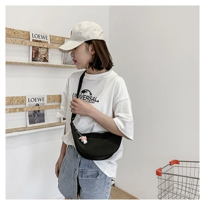 Black crescent nylon crossbody bag with cute astronaut charm shown on a casual outfit