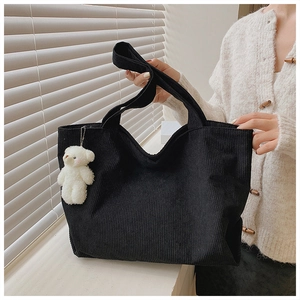 Detailed texture of black corduroy tote bag with cute white plush bear keychain accessory