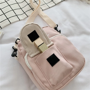 Detail of pink canvas crossbody bag showing velcro front pocket and zipper main compartment