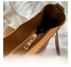 Detail of premium golden metal zipper and smooth texture on brown leather tote bag