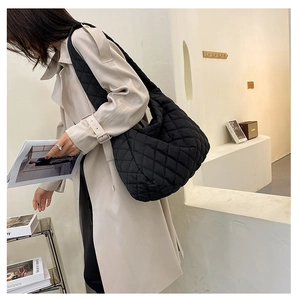 Detailed view of the black quilted shoulder bag with soft nylon padding and wide strap