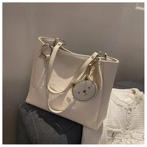 Detail of cream white tote bag with embossed bear patterns and cute charm pendant