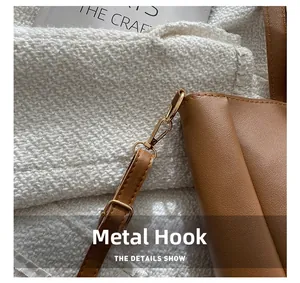 Detail of the brown leather tote featuring golden hardware hooks and neat stitching