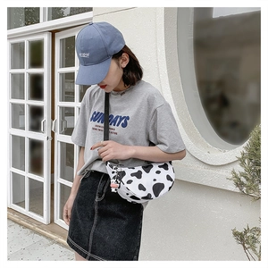 Detail of cow print crossbody crescent bag with adjustable strap and cute cow pendant