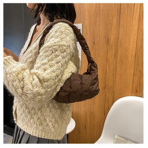 Detail of dark brown quilted puffer shoulder bag showing soft texture and stitching