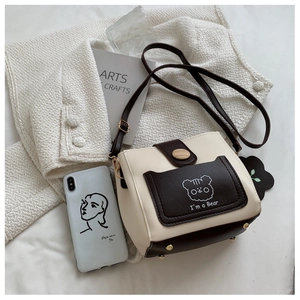 Detail of crossbody bucket bag with contrast stitching and bear graphic on fabric