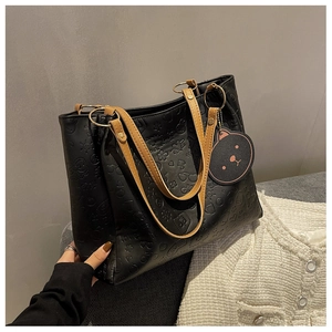 Detail of black leather tote bag with cartoon embossed texture and brown handles