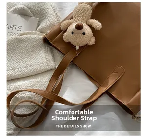Detail of comfortable brown faux leather tote straps with cute plush bear pendant decoration