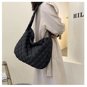Detail of black quilted puffer bag with diamond pattern and soft padded strap on shoulder