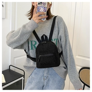 Mirror selfie showing black fuzzy lamb wool mini backpack worn as a trendy chest bag