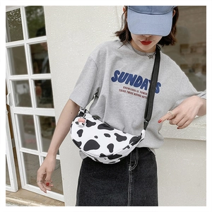 Detail of cow print nylon crescent bag with adjustable wide strap shown on model