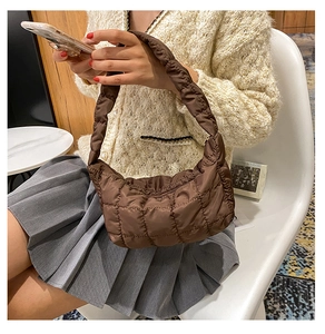 Detail view of large dark brown quilted crescent bag with pleated handle texture
