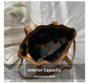 Internal capacity of the large brown tote bag showing phone and cosmetics inside