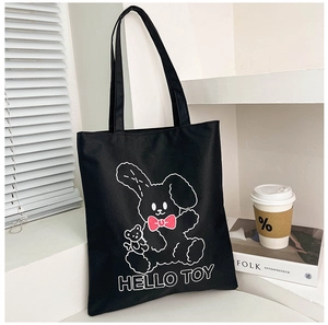 Detail of black canvas tote bag featuring a cute cartoon bear print and pink bow decoration