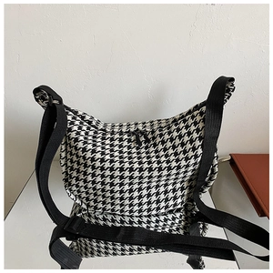 Top view of houndstooth crossbody bag featuring dual zippers and adjustable black strap