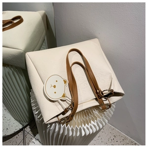 Detail of cream tote bag with embossed cartoon patterns and brown leather strap
