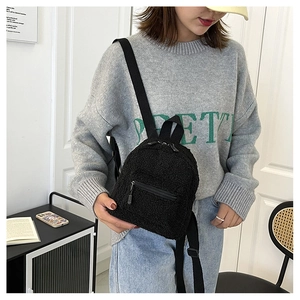 Close-up of fluffy black faux fur mini backpack with durable nylon straps on model