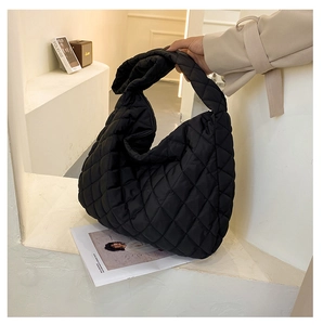 Detail of a large black quilted cloud puffer bag with soft ruched texture and wide handle