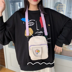 Detail of cute canvas crossbody bag with purple strap and lollipop badge on pocket