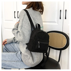 Detail view of mini black faux shearling backpack showing soft texture and nylon straps