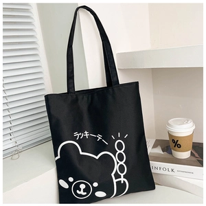 Detail of black canvas tote bag featuring a minimalist white cartoon bear print and Japanese text