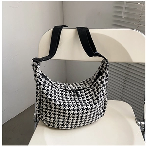 Detail of houndstooth crossbody bag featuring black nylon strap and adjustable buckle