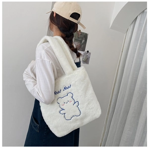 Gros plan d'un sac cabas en peluche blanche avec broderie ours bleue et texte Bear Bear