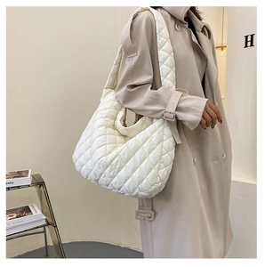 Close-up of white quilted puffer tote bag on model showing soft texture and large capacity