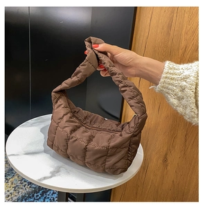 Detail of soft brown quilted hobo bag featuring wide handle and puffed stitching texture
