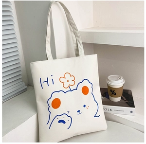 Detail of white canvas tote bag featuring a cute blue cartoon bear with orange flower