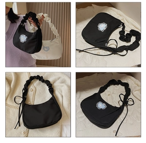 Detail of ruched handle, bow ribbon, and whale embroidery on the pleated underarm bag